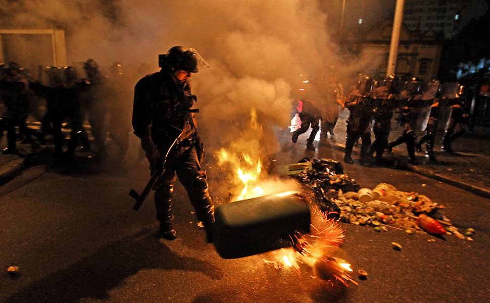 Policial do Choque chuta cesto de lixo de uma fogueira feita por manifestantes