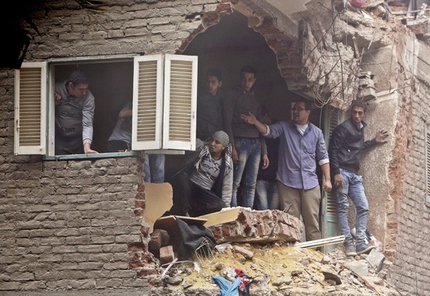 Vizinhos observam operação de resgate através de vão na parede causado pelo desabamento que deixou vários mortos no Cairo (Foto: Amr Nabil/AP)