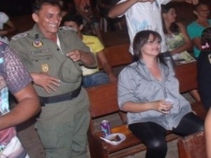 Militar Hugo em pé e a esposa sentada ao lado em evento