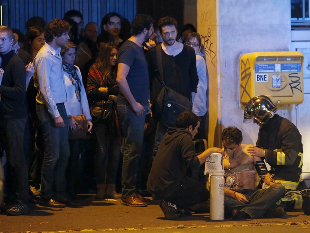 Homem é socorrido após tiroteio perto do Bataclan, conhecida sala de espetáculos de Paris, na França (Foto: Christian Hartmann/Reuters)