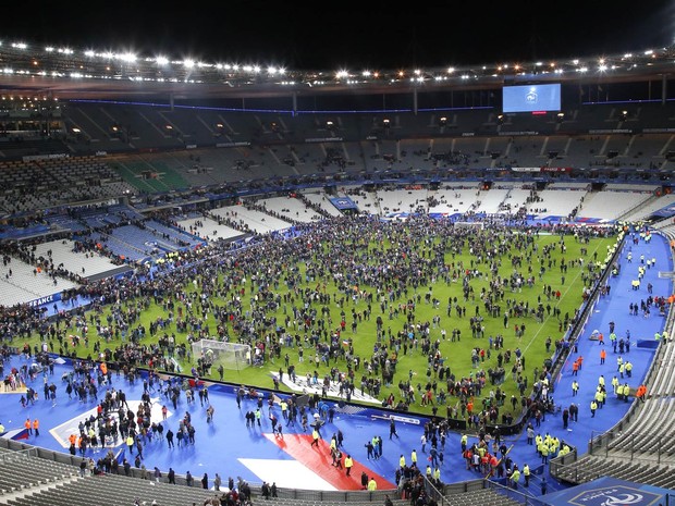 Gramado do Stade de France ocupado por parte do público após explosão. O estádio fica em Saint Denis, perto de Paris. Explosões foram ouvidas durante o jogo (Foto: Michel Euler/AP)