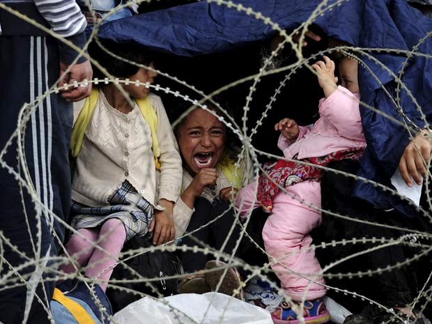 Criança chora ao esperar com sua família neste sábado (22) na fronteira da Grécia para entrar na Macedônia (Foto: REUTERS/Ognen Teofilovski)