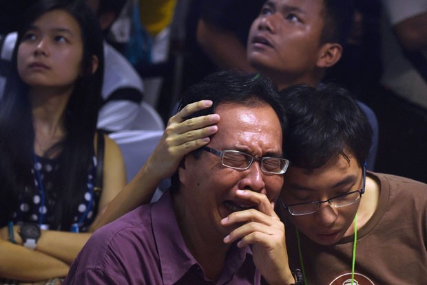 Parentes de passageiros do avião da AirAsia que caiu no mar choram no aeroporto de Juanda, em Surabaya, na Indonésia, ao receberem a notícia da localização dos destroços da aeronave nesta terça-feira (30) (Foto: Manan Vatsyayana/AFP)