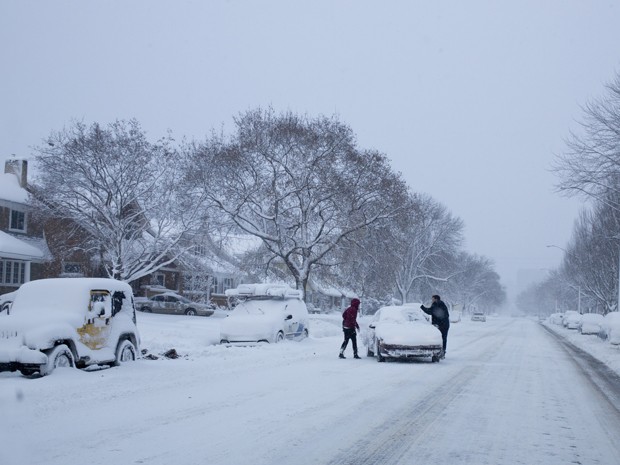 Pessoas tentam tirar veículo do meio de estrada em Lake Michigan Drive, no Michigan, na terça-feira (18) (Foto: AP Photo/The Grand Rapids Press, Joel Bissell )