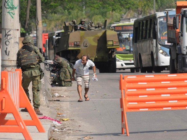 Homem se abaixa com medo de tiros na Avenida Brasil, no Rio de Janeiro, após o início de um tiroteio na altura da Fiocruz, na Zona Norte da cidade. A via foi fechada na tarde desta quarta-feira (1º) pelo Batalhão de Policiamento de Vias Expressas (BPVE) (Foto: Sandro Vox/Agência O Dia/Estadão Conteúdo)