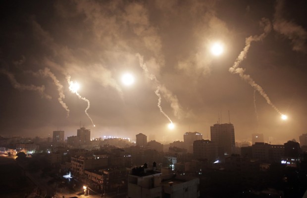 Não são fogos de artifício. São bombardeios perpetrados contra a Faixa de Gaza na madrugada desta terça-feira (29). Em 21 dias de confrontos, mais de 1,1 mil pessoas morreram e cerca de 6,2 mil ficaram feridas (Foto: AP Photo/Khalil Hamra)