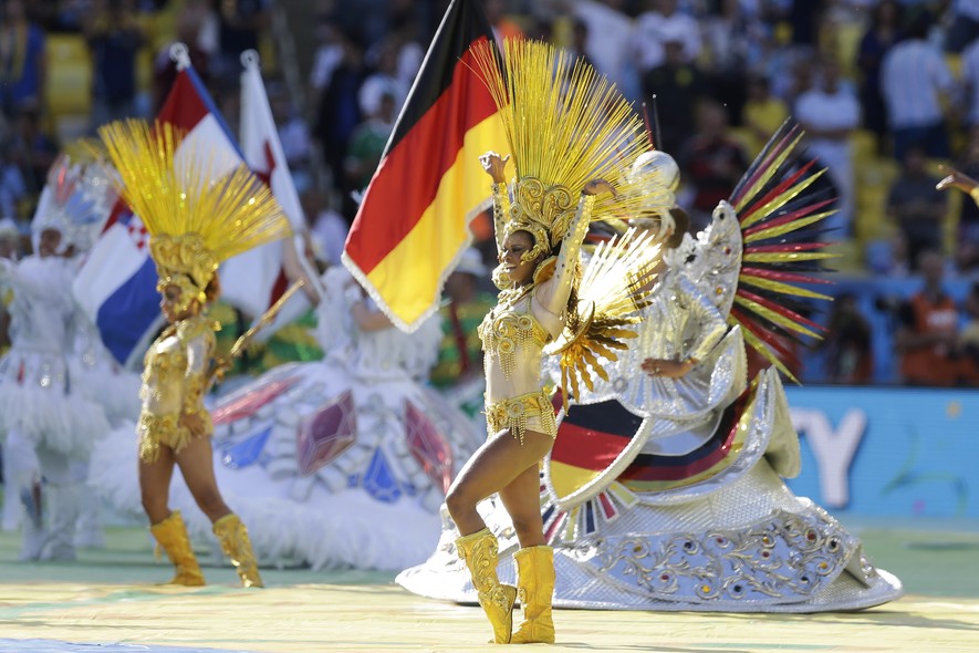 Bailarinas se apresentam em frente à bandeira alemã, país que disputará a final da Copa