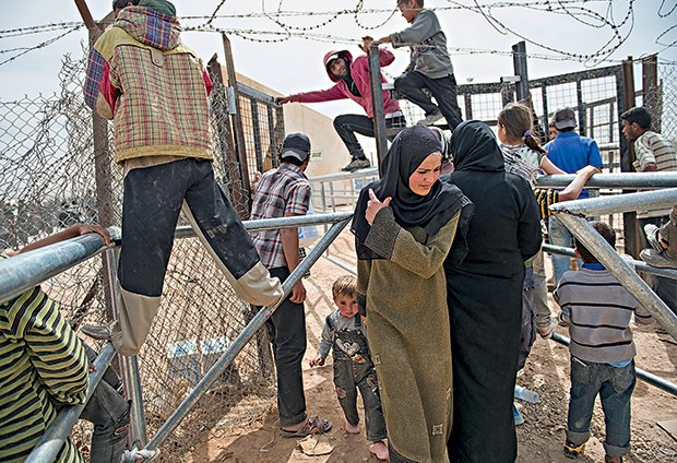 Um grupo tenta obter suprimentos em Zaatari, na Jordânia (Foto: Lynsey Addario/The New York Times)