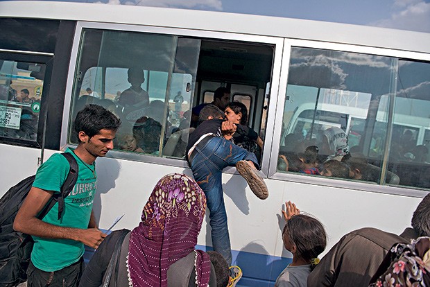 ADEUS AO INFERNO 1. Mulher puxa a filha para dentro de ônibus na Síria, com destino ao Iraque (Foto: Lynsey Addario/The New York Times)