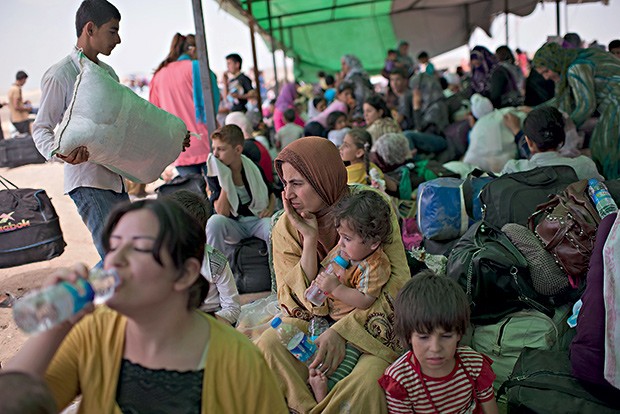 2. Gulchin, a mulher no centro, com o filho no colo, espera para embarcar em um ônibus (Foto: Lynsey Addario/The New York Times)