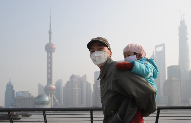 Homem carrega criança nas costas em Xangai, China. Os dois usam máscaras por conta da forte nuvem de poluição na cidade (Foto: ChinaFotoPress via Getty Images)