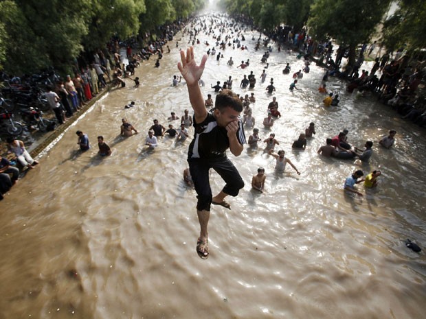 Crianças brincam em canal para refrescar o calor que atinge o Paquistão (Foto: Mohsin Raza/Reuters)