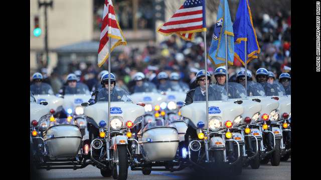 Police on motorcycles lead as United States President Obama and first lady Michelle Obama walk along Pennsylvania Avenue during the parade.