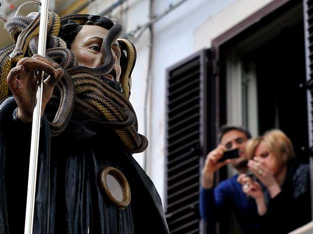 Moradores fotografam a imagem de São Domingos coberta por cobras . Foto: AFP