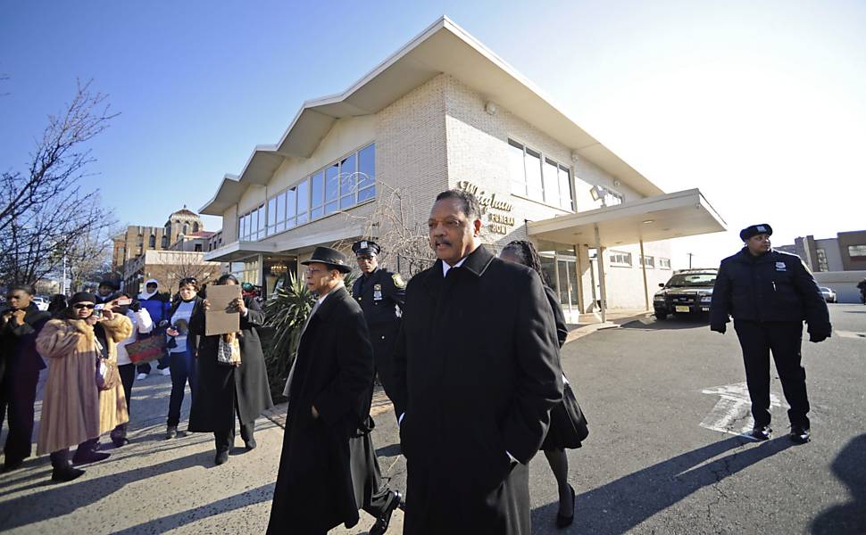 O reverendo Jesse Jackson (ao centro) deixa a funerária em direção à igreja batista New Hope, em Newark, Nova Jersey, onde acontece o funeral de Whitney Houston