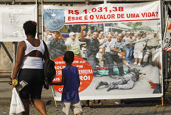 Mulher e criança passam por faixa colocada por PMs grevistas no Rio; categoria quer reajuste salarial