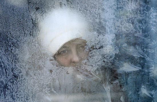 Mulher observa frio através de janela de um ônibus com vidro congelado na cidade de Kiev, na Ucrânia