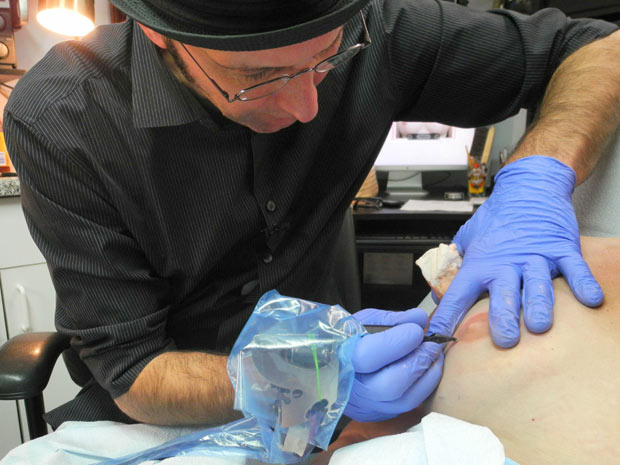 Tatuador desenha mamilo em mulher que teve a mama extirpada (Foto: Fabienne Faur / AFP)