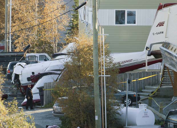 Destroços de pequeno avião que caiu nesta quinta-feira (22) em conjunto residencial em Yellowknife, no Território do Noroeste, no Canadá. Duas pessoas morreram e sete ficaram feridas, todas elas a bordo do avião. Na queda, um carro foi destruído, segundo testemunhas (Foto: AP)