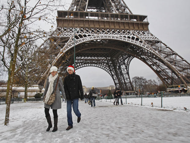 Pedestres caminham pela torre Eiffel coberta de neve, em Paris