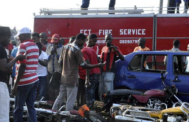 Pessoas se reúnem ao redor de local de explosão na Nigéria nesta segunda-feira (14); dezenas morreram no ataque (Foto: Gbemiga Olamikan/AP)