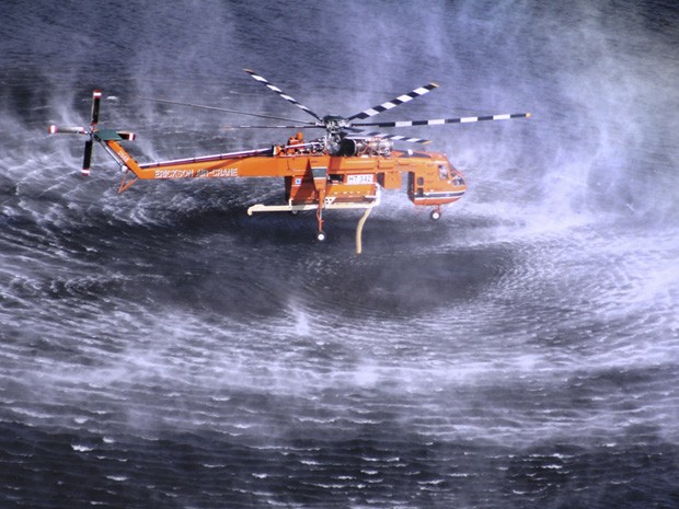 Avião capta água para combater as chamas em um incêndio de grandes proporções na Austrália. (Foto: Country Fire Authority/AP)