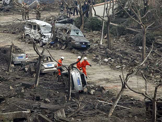 Equipes de resgate vasculham estrada danificada e coberta com destroços após explosão em um oleoduto em Qingdao. (Foto: Aly Song / Reuters)